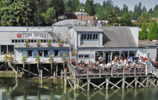 Exterior of Tides Tavern with people sitting on the outdoor deck.