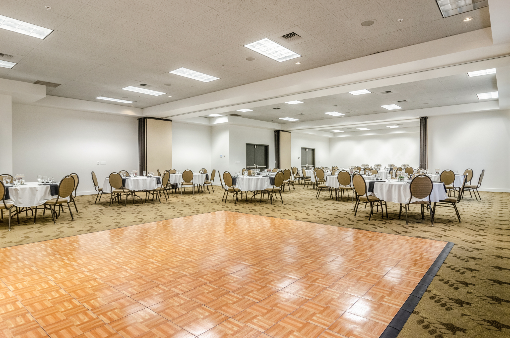 Hotel ballroom with tables, chairs, and dance floor.