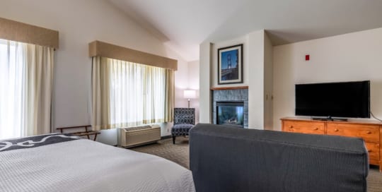 Hotel suite with king bed, fireplace, sofa and television.